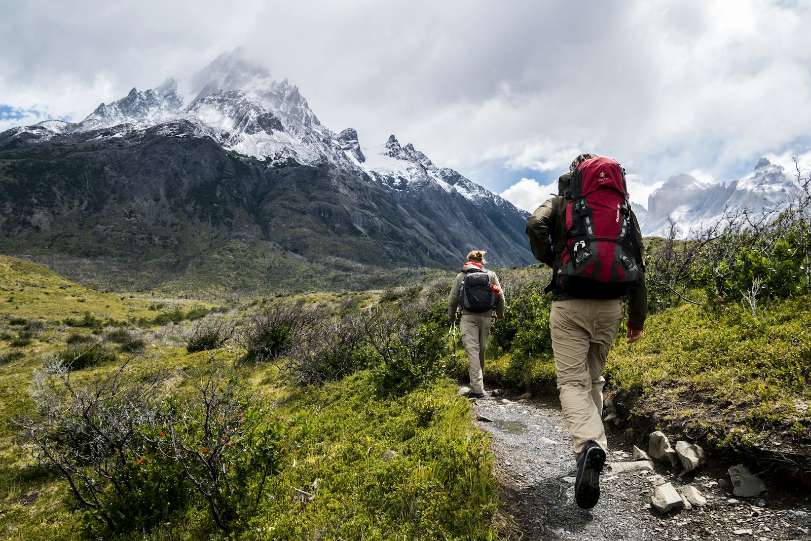 A hiker adjusting a daypack near a scenic trailhead